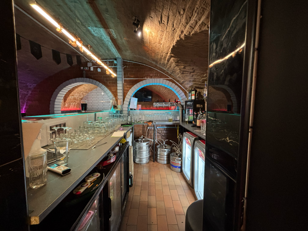 A The Black Door Darts & Sport Bar bárpultja csapolt sörökkel, italválasztékkal és hangulatos pincehelyiséggel.